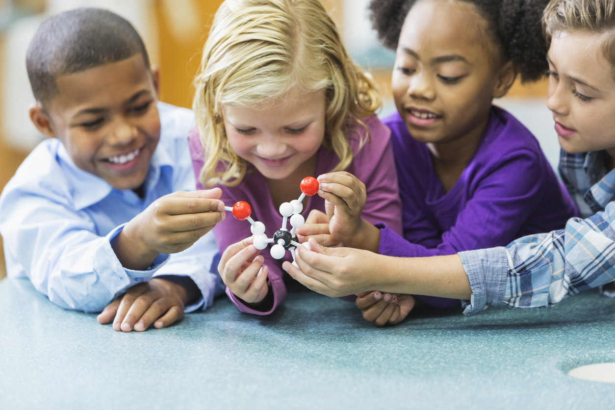 Multi-ethnic children in science class with model